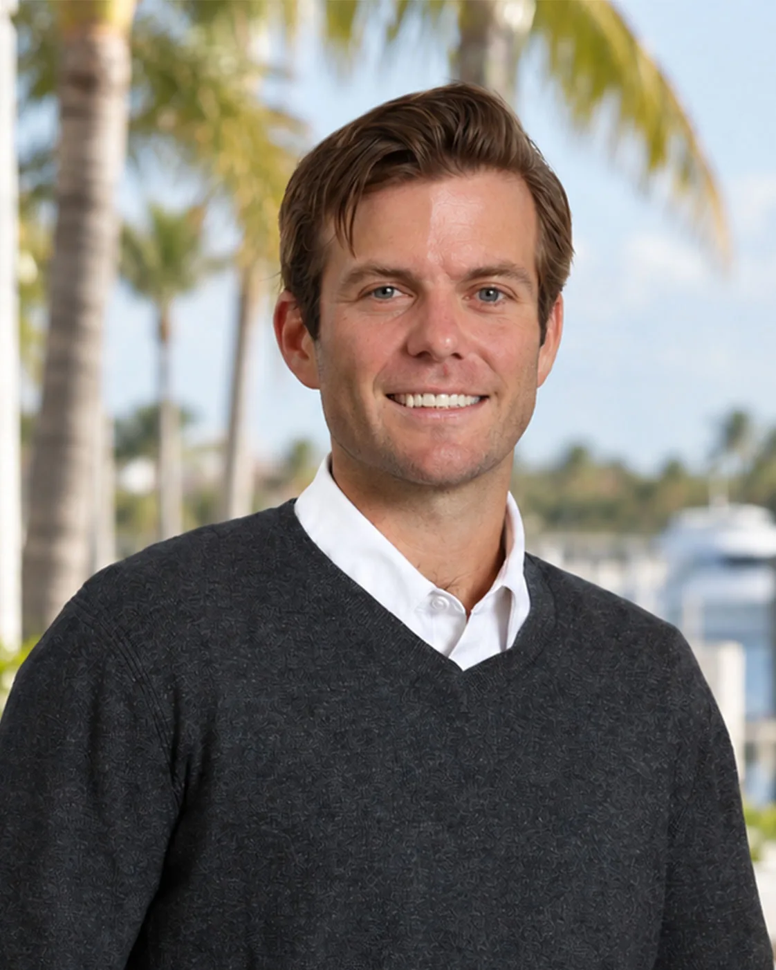 Portrait of Michael Riebesell, in a dark sweater, palms and water behind him