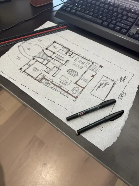A hand-drawn floor plan sketch on tracing paper with two pens