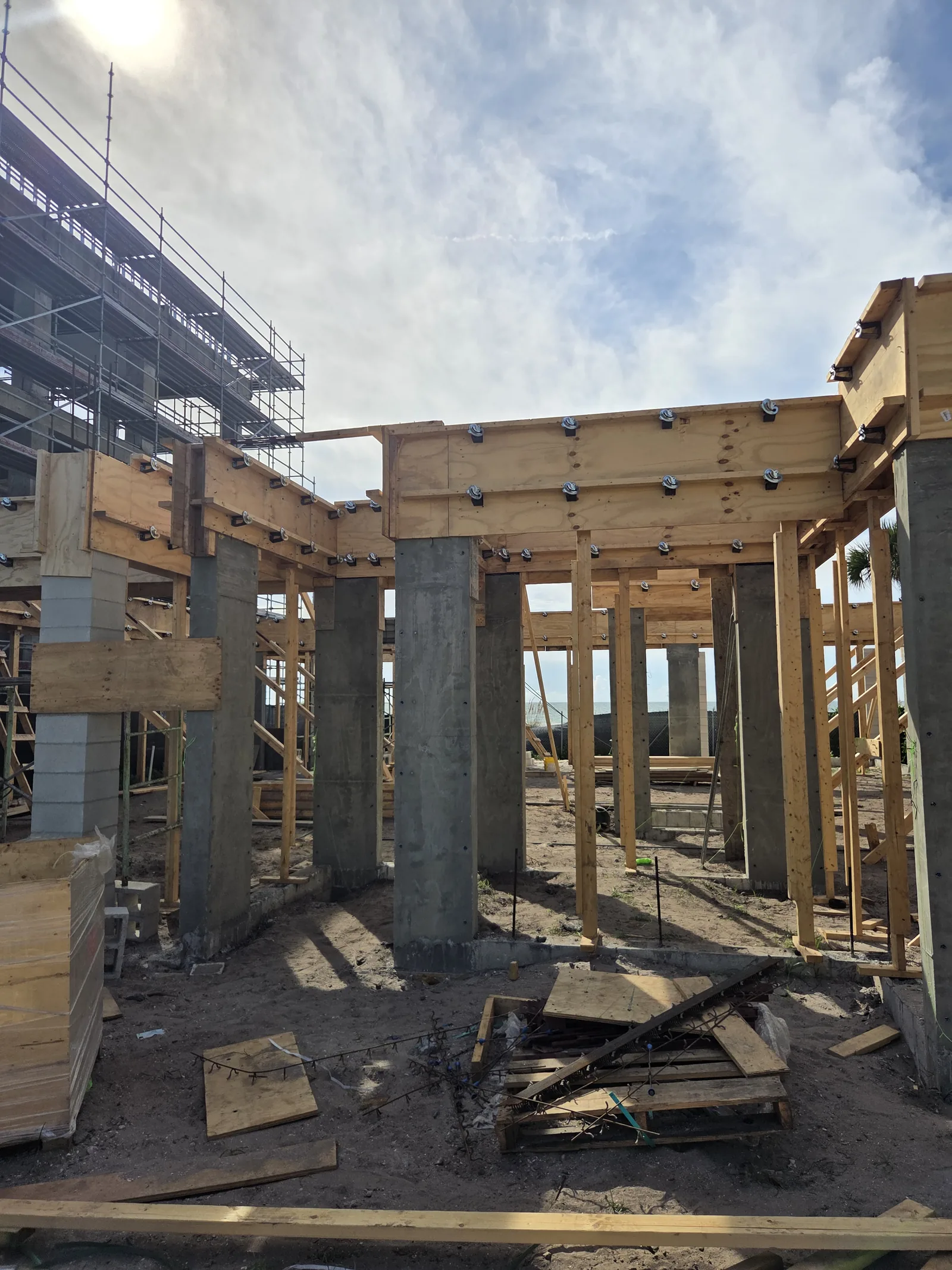 A coastal home under construction, its timber floor frame set on tall concrete columns