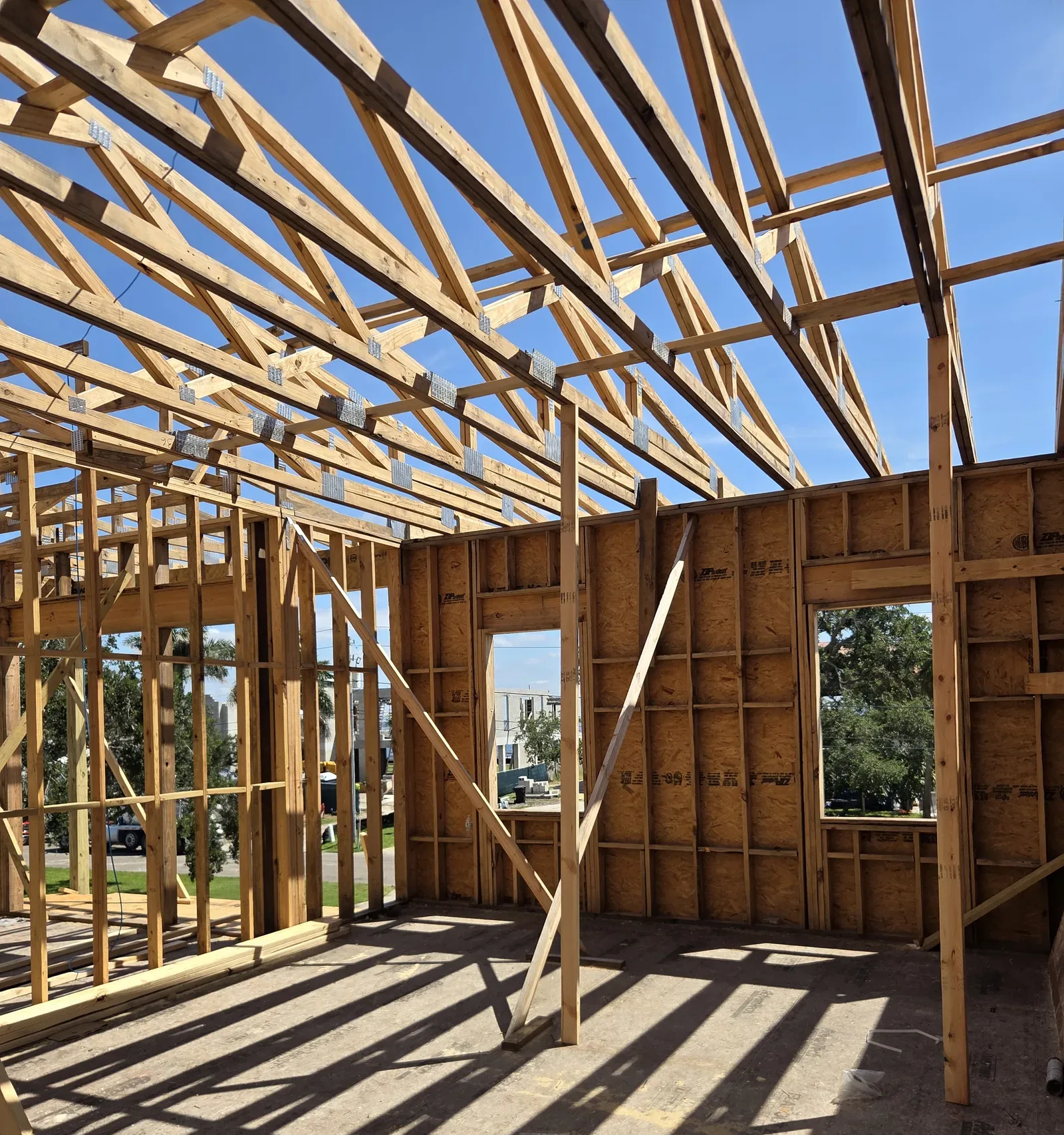 Timber wall and roof framing of a house under construction against a blue sky