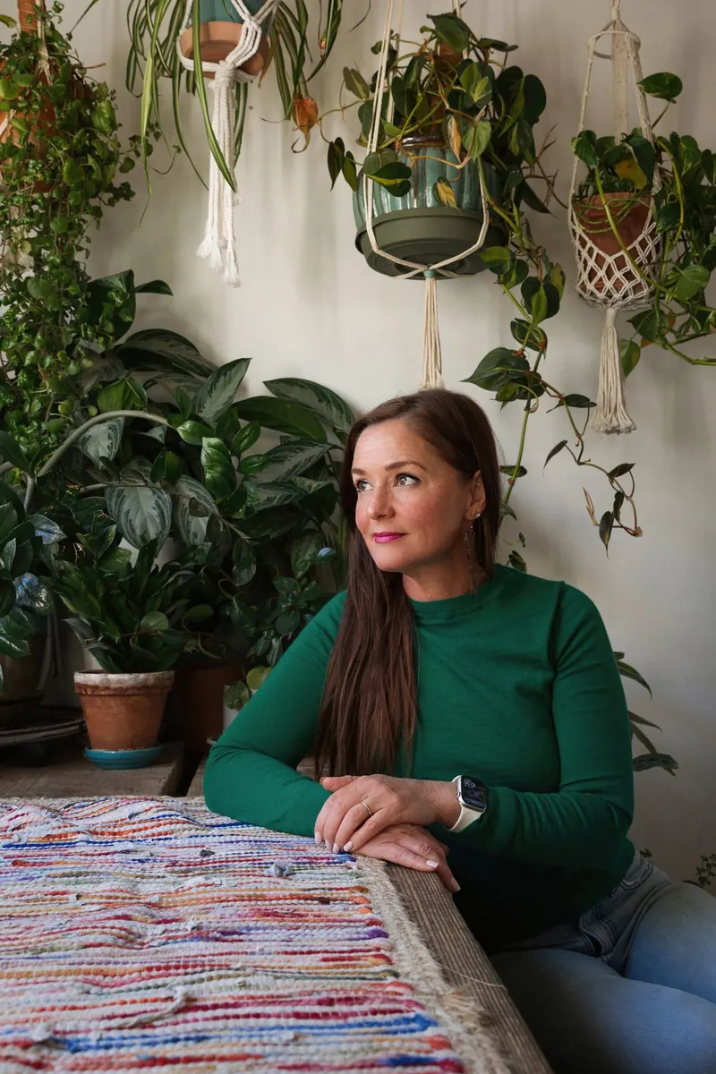 Anya Gossage of AIP Wellness sitting at a table surrounded by houseplants