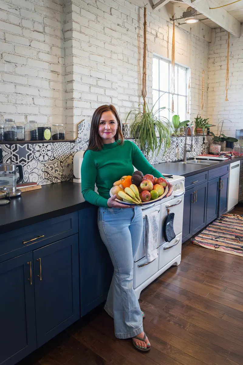 Anya Gossage holding a bowl of fresh fruit in her kitchen