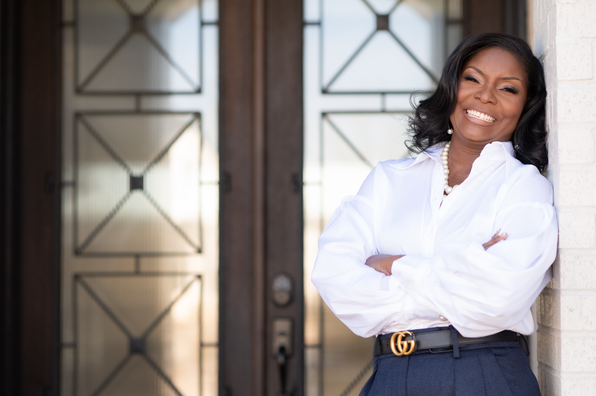 Coach Michelle smiling in a white blouse, standing with her arms crossed