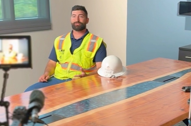 A client on camera in a safety vest, being filmed at his business