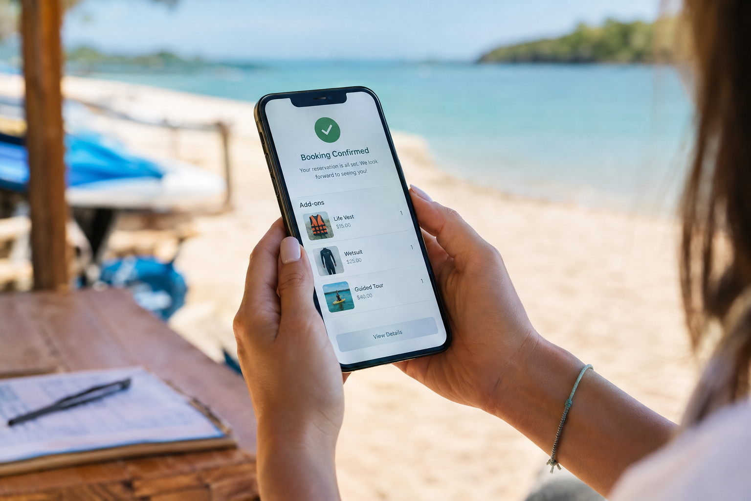 Customer reviewing rental booking confirmation with add-on items on her smartphone at a beachside rental stand