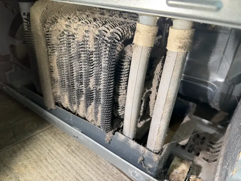 Refrigerator condenser coils clogged with dust and lint before cleaning