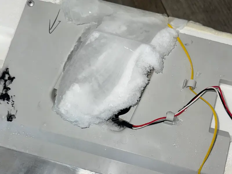 Thick ice buildup over a refrigerator evaporator fan cover found during a repair in Charlotte, NC