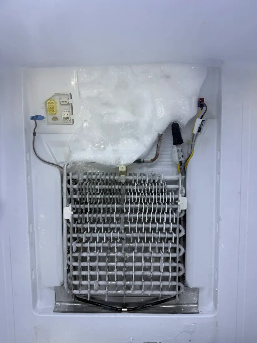 Refrigerator evaporator coil buried under ice from a failed defrost system