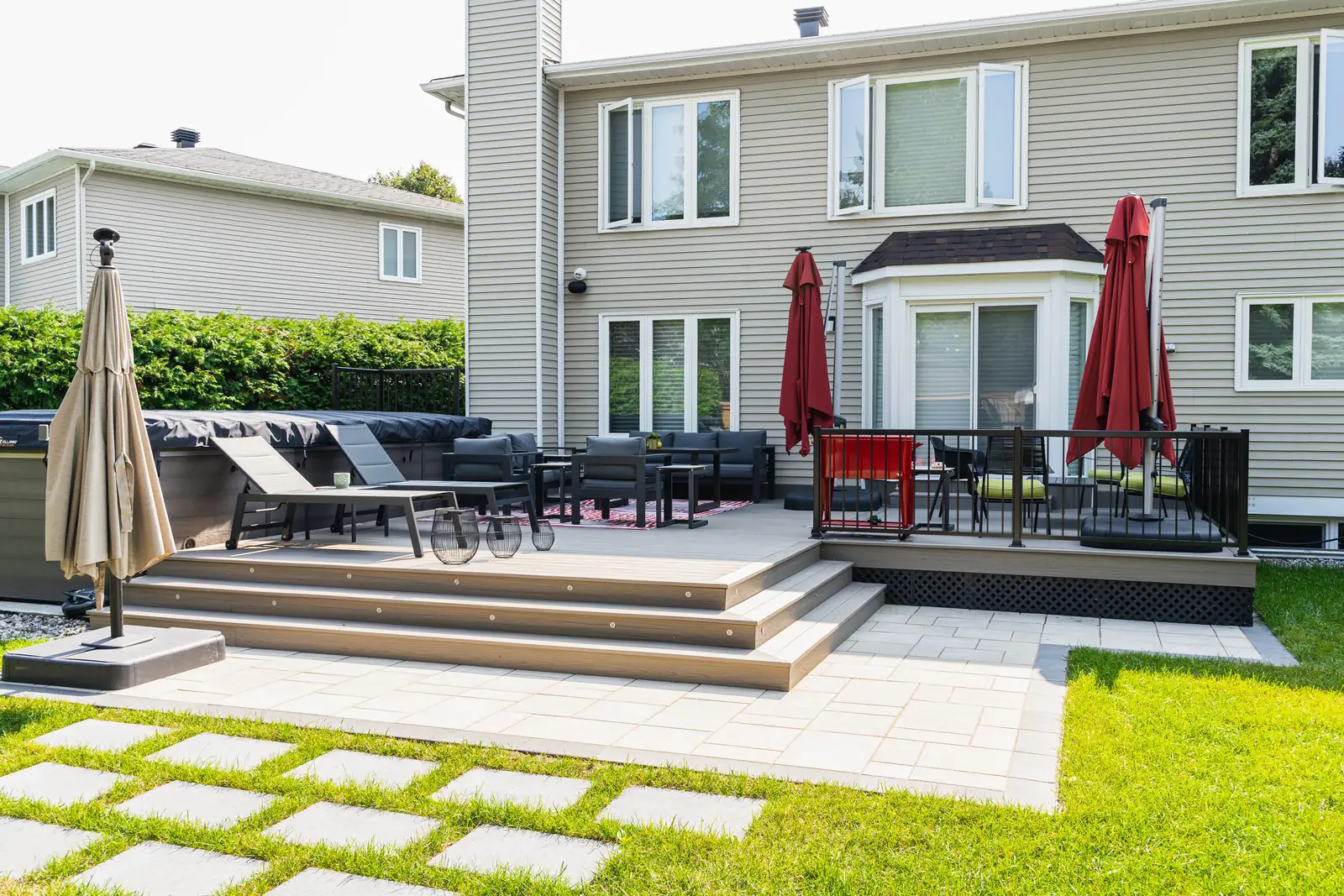 A two-level composite deck with wide steps, black railings and lounge furniture, built by Elie's Fencing