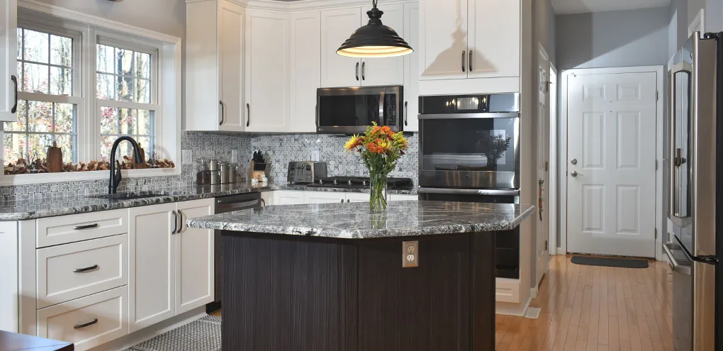 A white kitchen with a dark wood island under a granite top and a black pendant light, from Kitchen Tune-Up