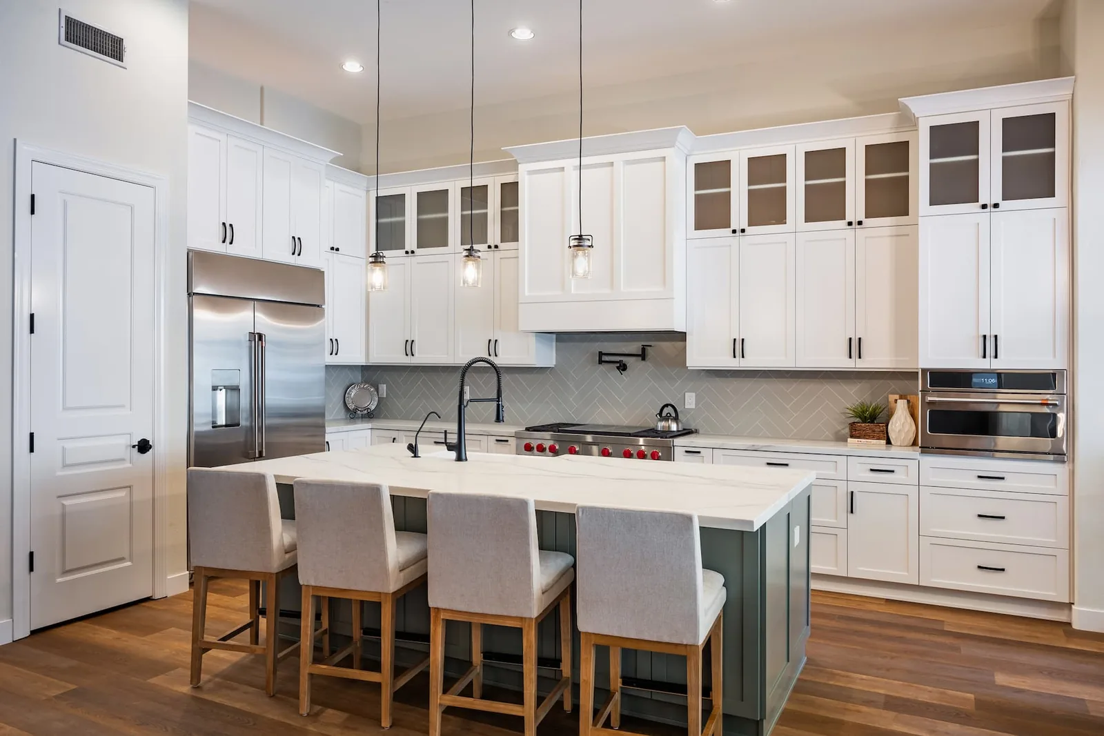 Kitchen renovation contractor lead generation case study: a white shaker kitchen with glass-front upper cabinets, a sage-grey island with a white quartz top and pendant lights, from Kitchen Tune-Up
