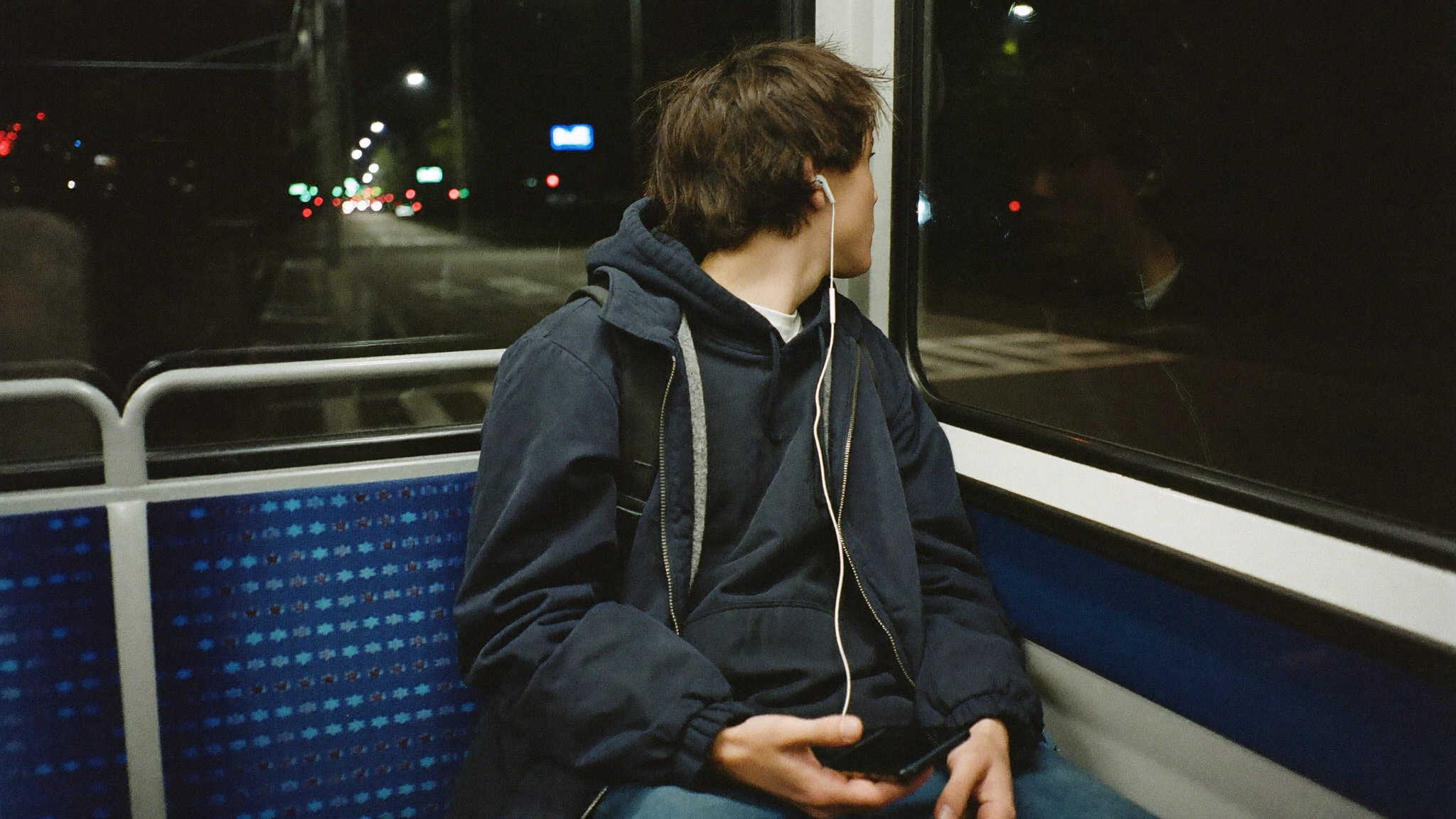 Mann sitzt in der Bahn und hört mit Kopfhörer nach seiner Nachtschicht ein Hörbuch auf Blinkist