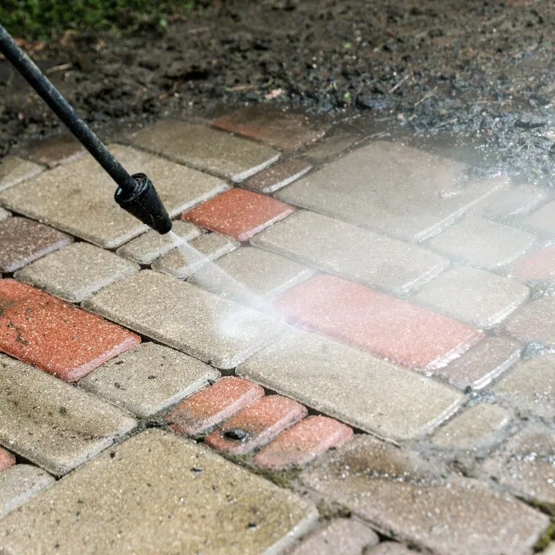 Close-up power washing removing salt stains and mildew from brick pavers on a Long Beach NY coastal home patio