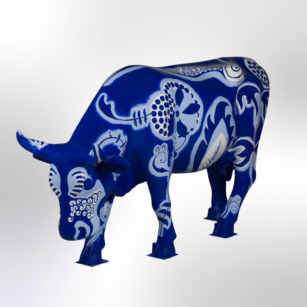A blue and white cow featuring folk art and floral motifs