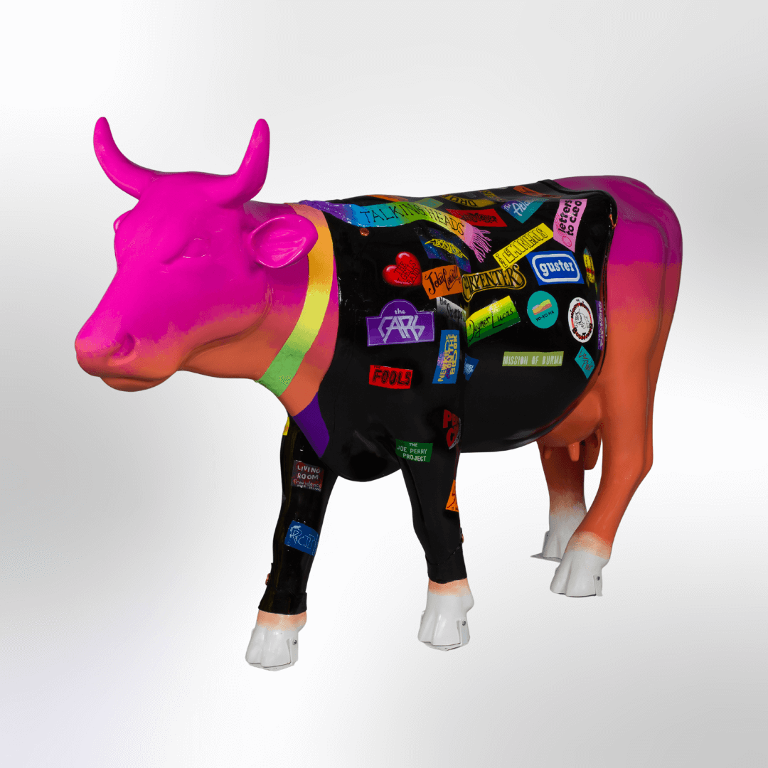 A bright cow wearing a black jacket covered in band logos