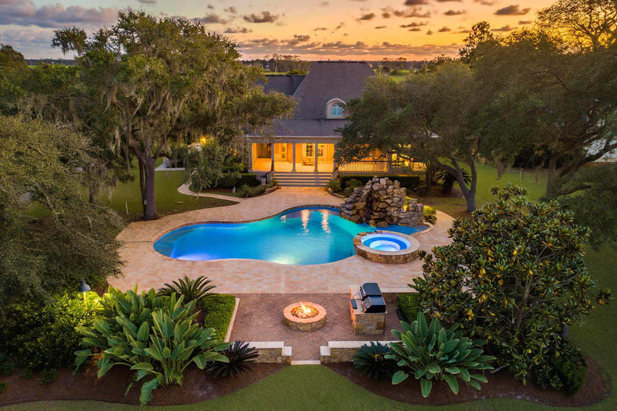 Custom luxury gunite pool with spa spillover and ambient sunset lighting