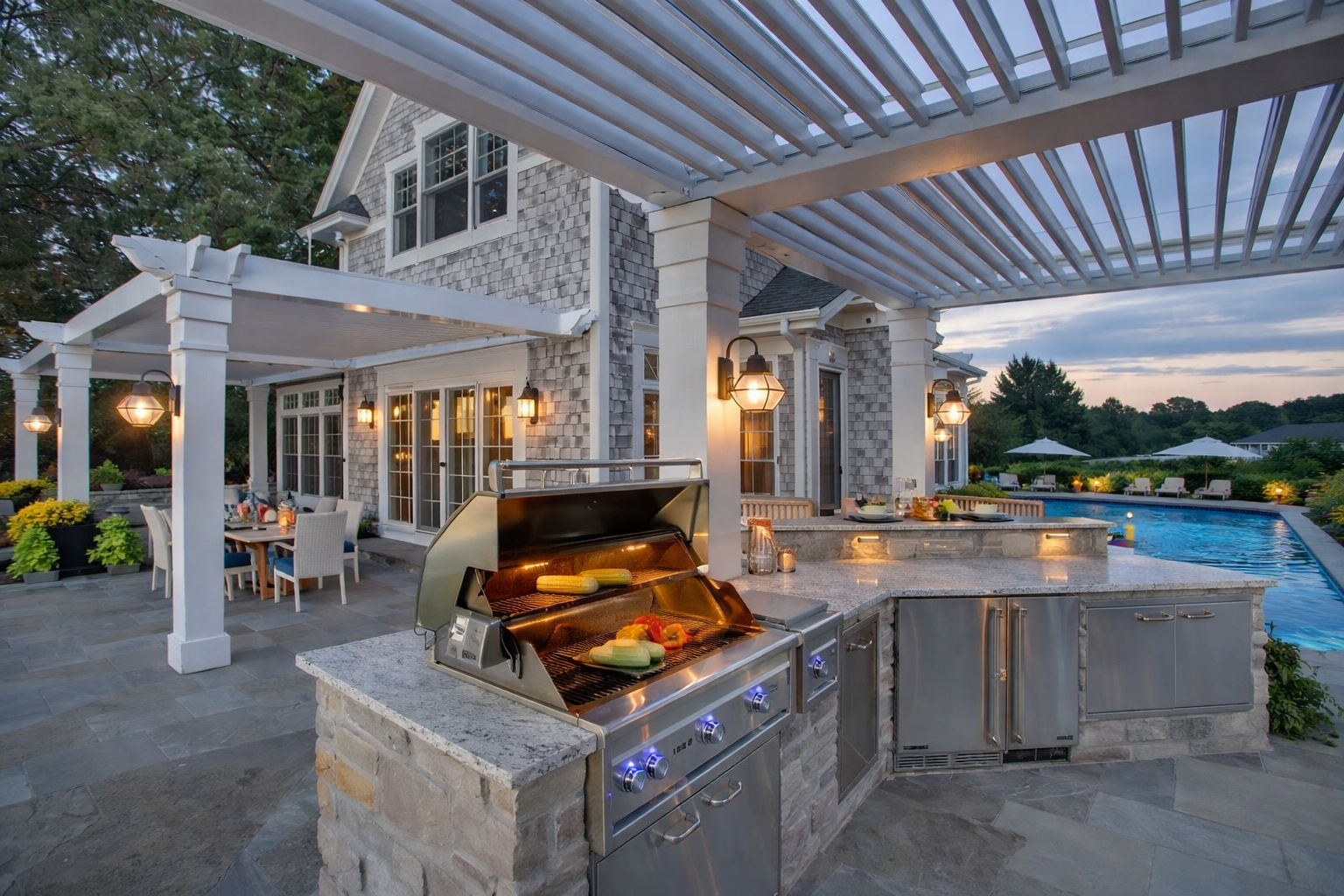 Custom outdoor kitchen island with built-in grill, stone countertop and seating