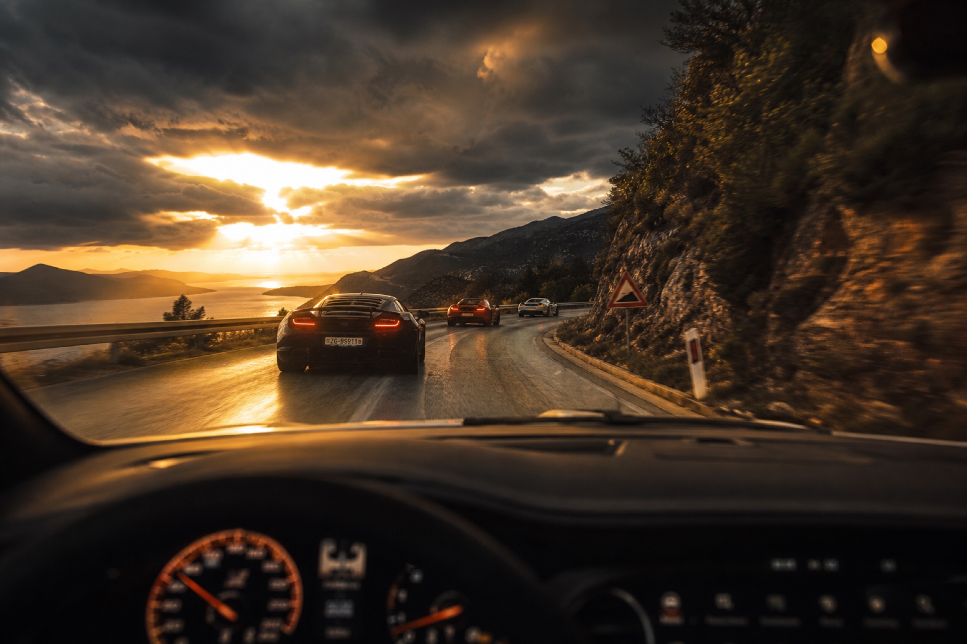 Convoy of supercars at golden dusk, shot from inside the chase car