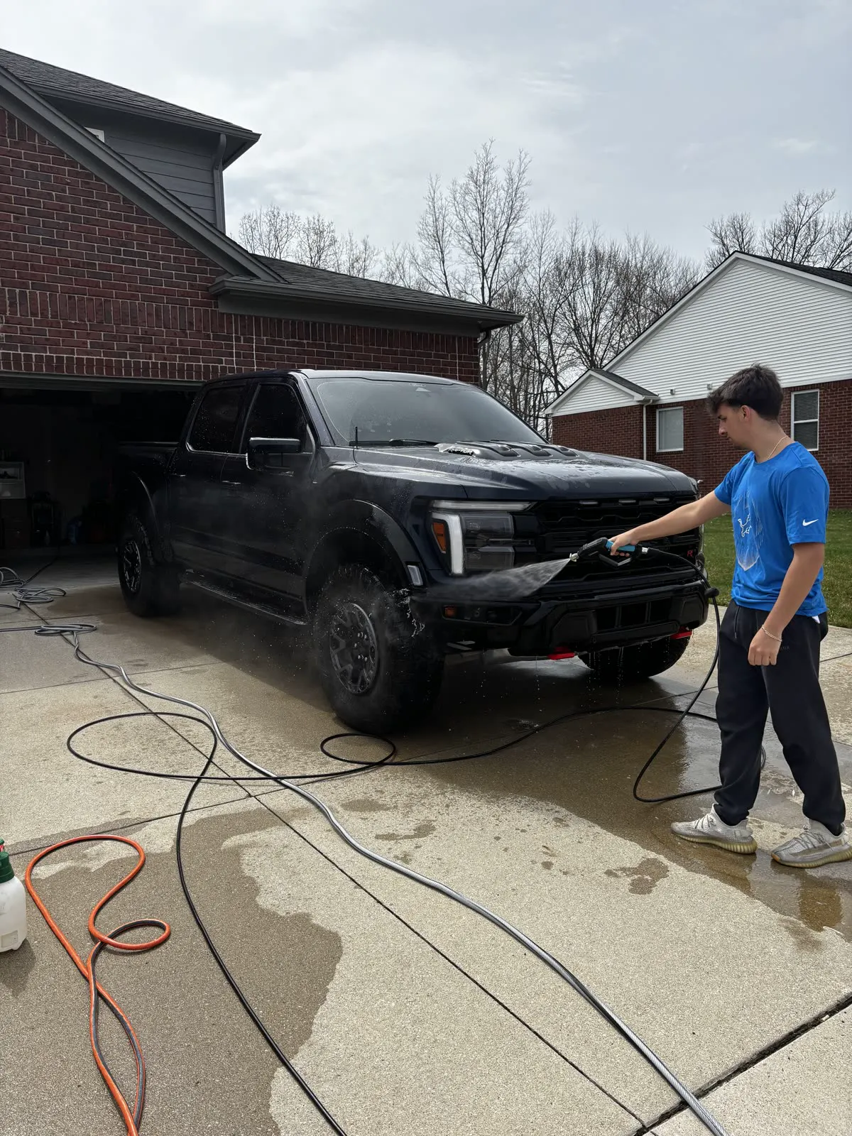 Technician pressure washing a lifted truck on location