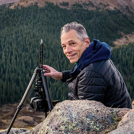 Greg Koorhan adjusting a camera on a tripod along the Continental Divide