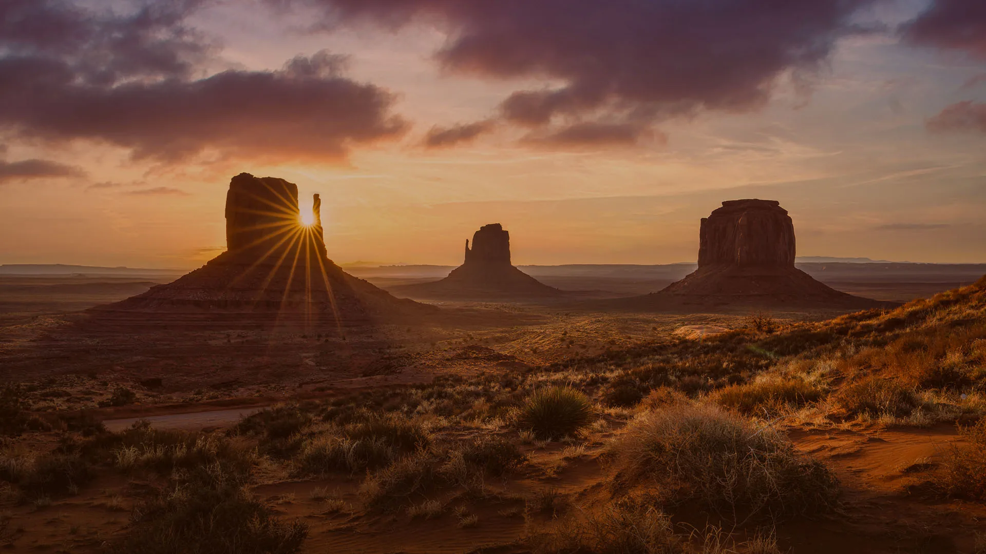 Sunburst over the Mittens rock formations at sunrise in Monument Valley, Utah