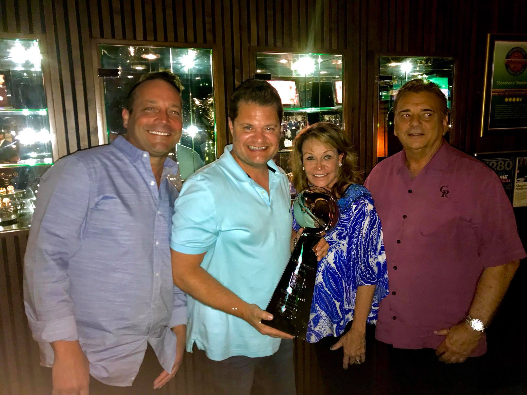 Storm Bennett holding the Heisman Trophy at a client dinner event in Denver