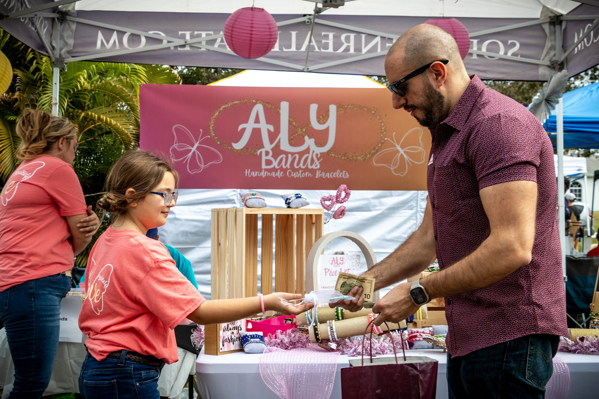 A young entrepreneur handing her product to an adult customer for cash