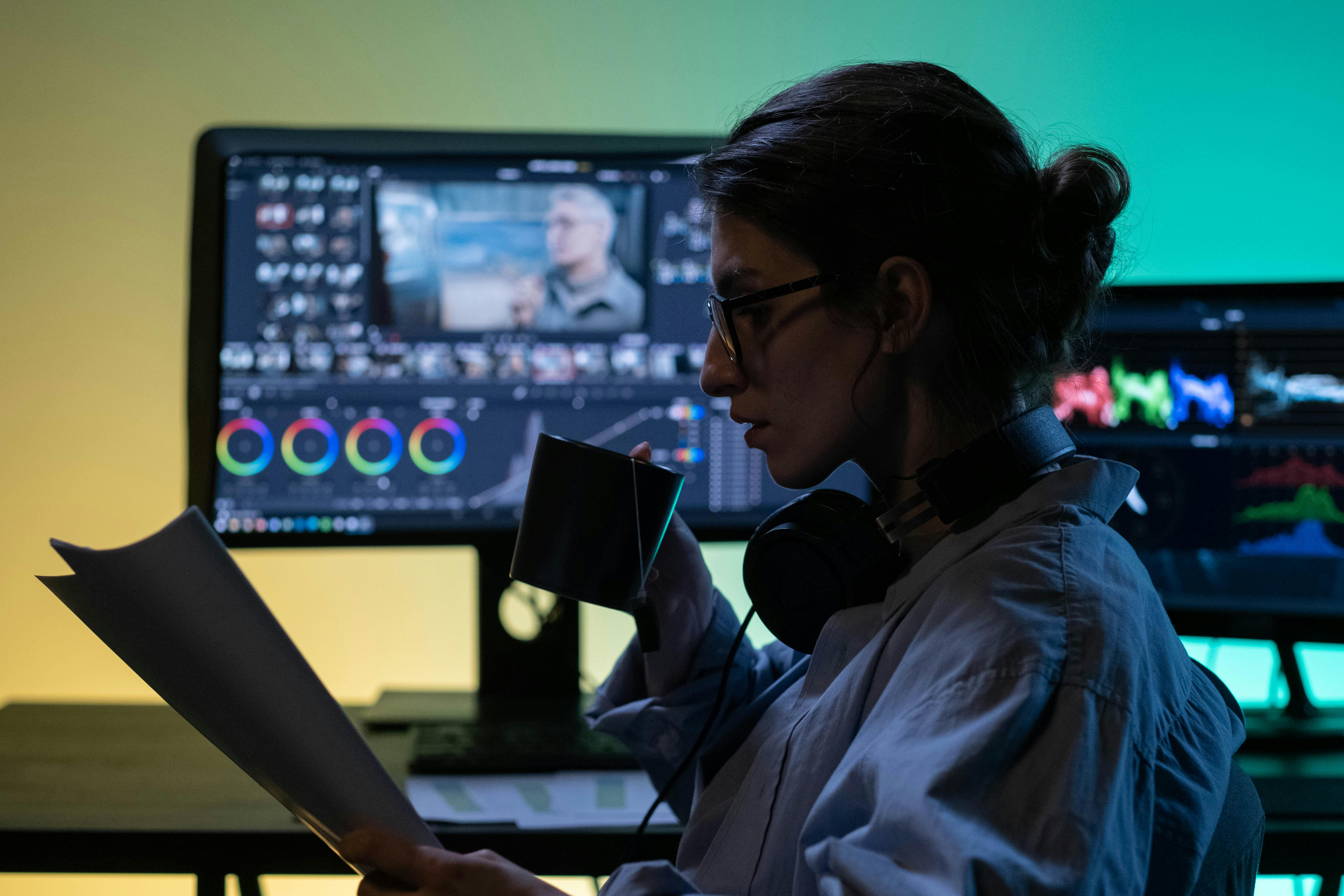 woman sitting in front of film video editing monitors