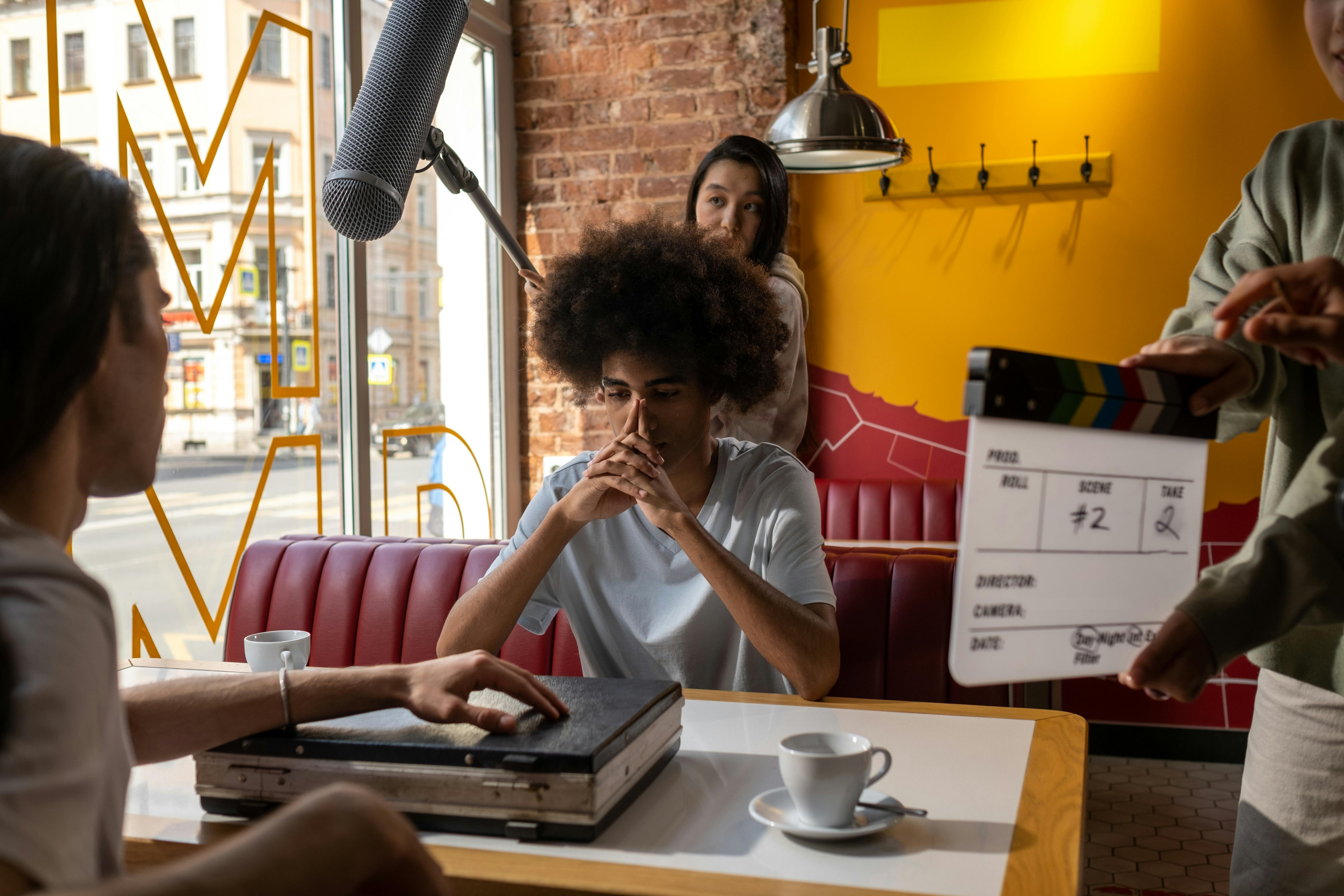 Man sitting in booth with boom mic overhead on a film set.
