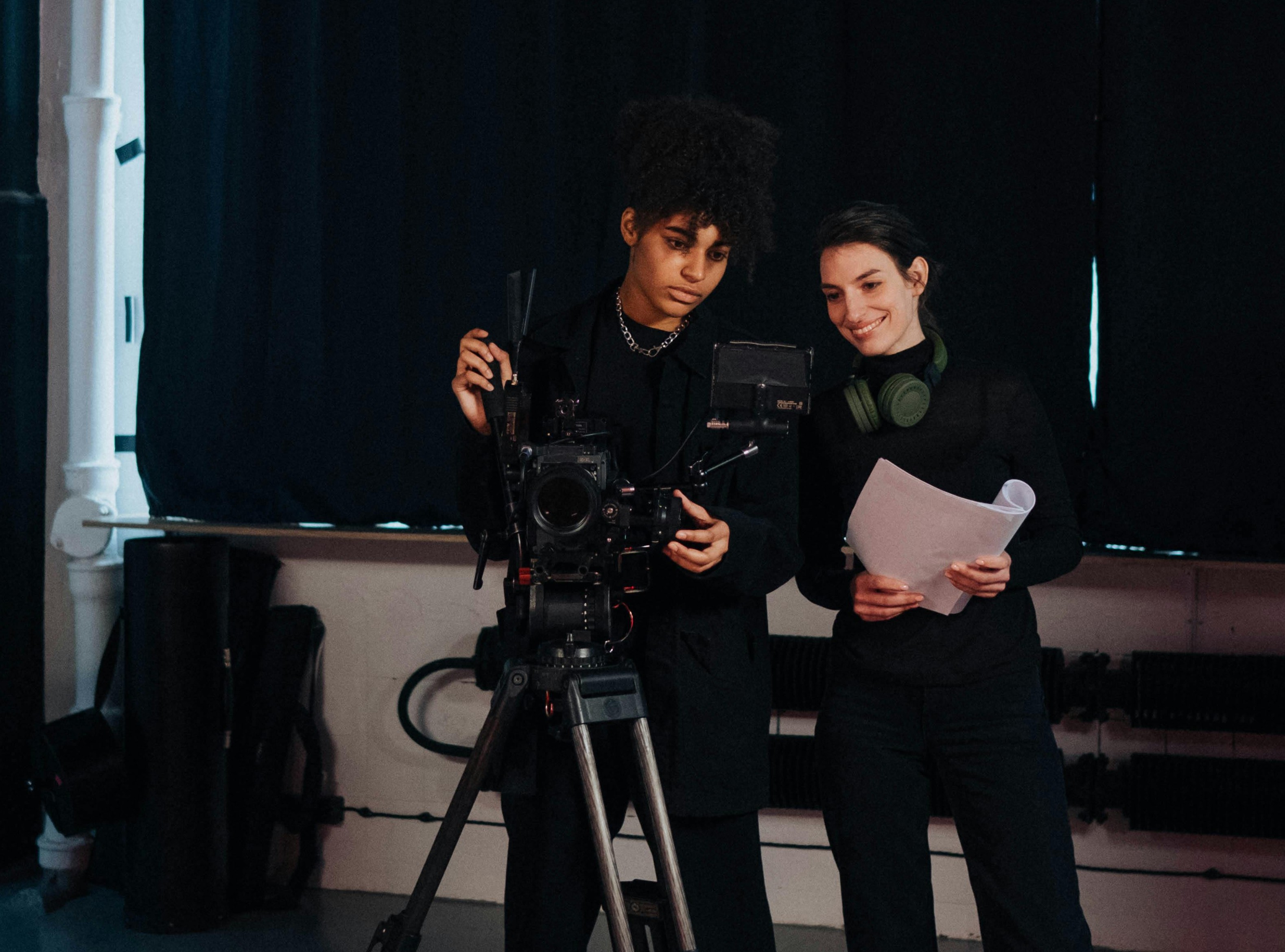 A woman behind a professional cinema camera, focused on capturing a powerful moment with femal director next to her.