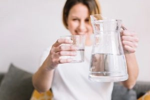 Person holding a glass and pitcher of water