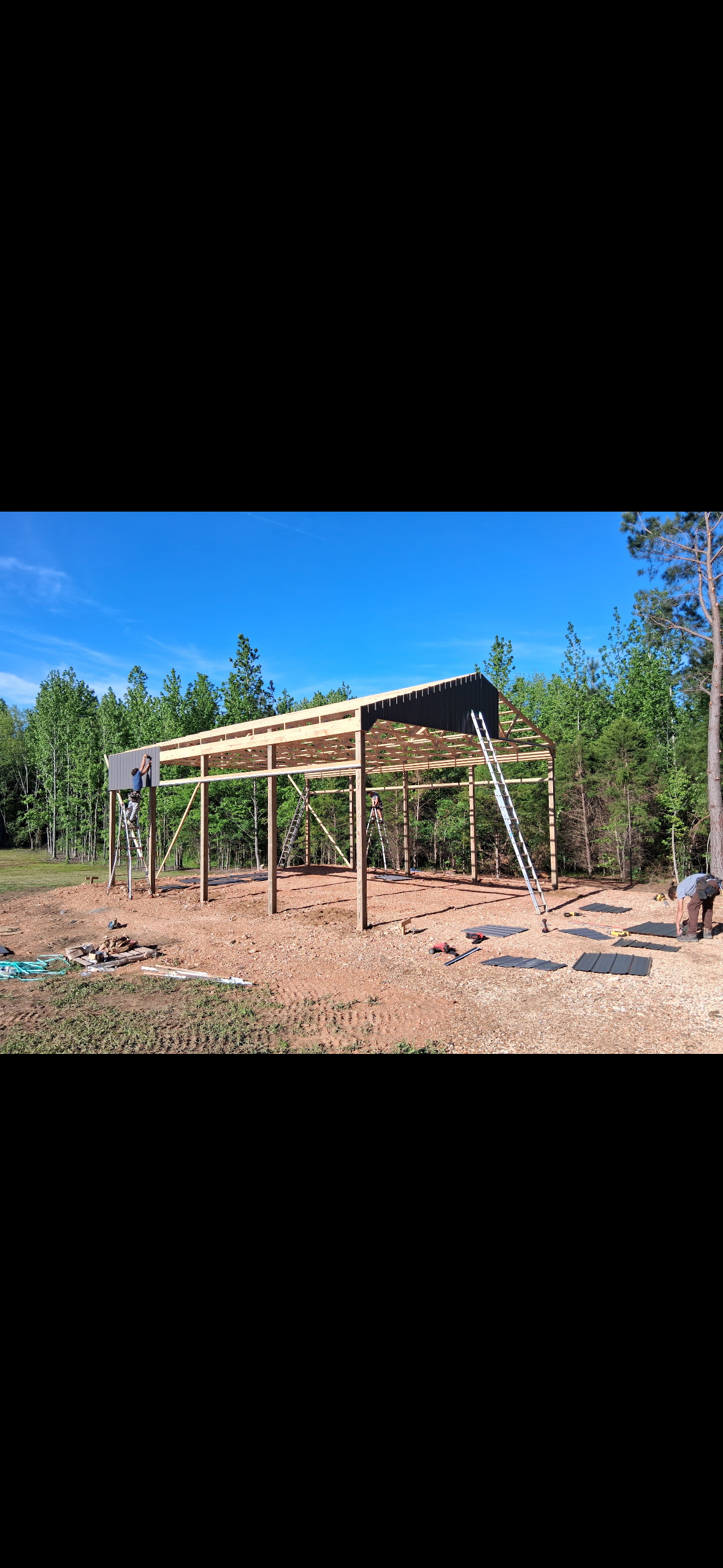 Open-Sided Pole Barn — Metal roof panel installation on the open-sided barn