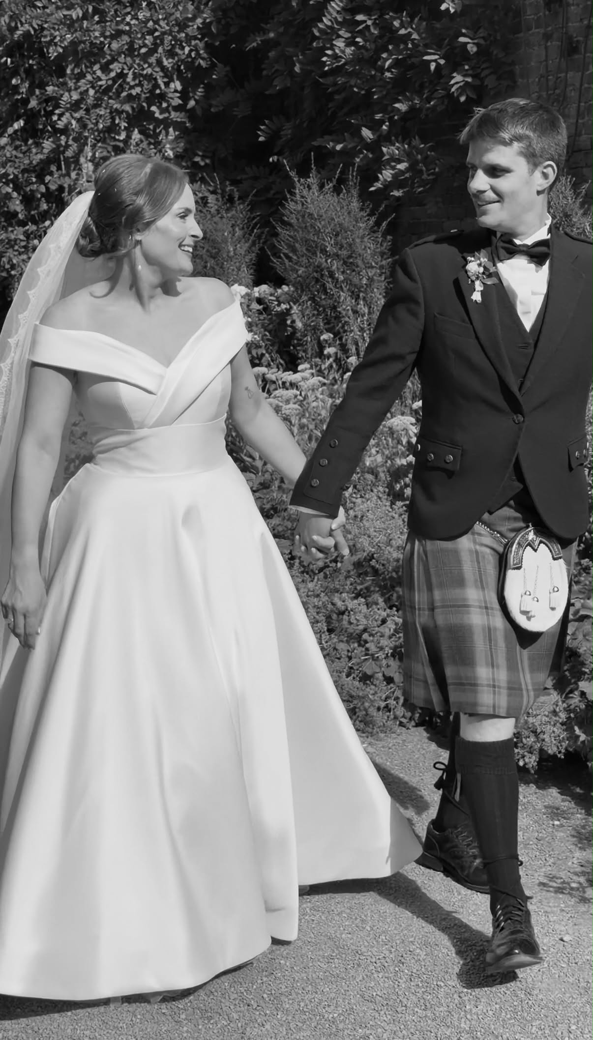 Bride and groom in a kilt walking hand in hand