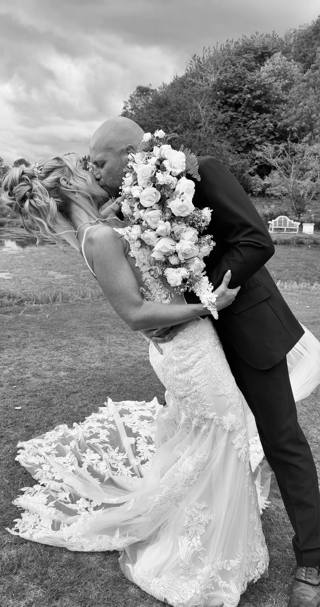 Couple kissing on the lawn, lace train behind the bride