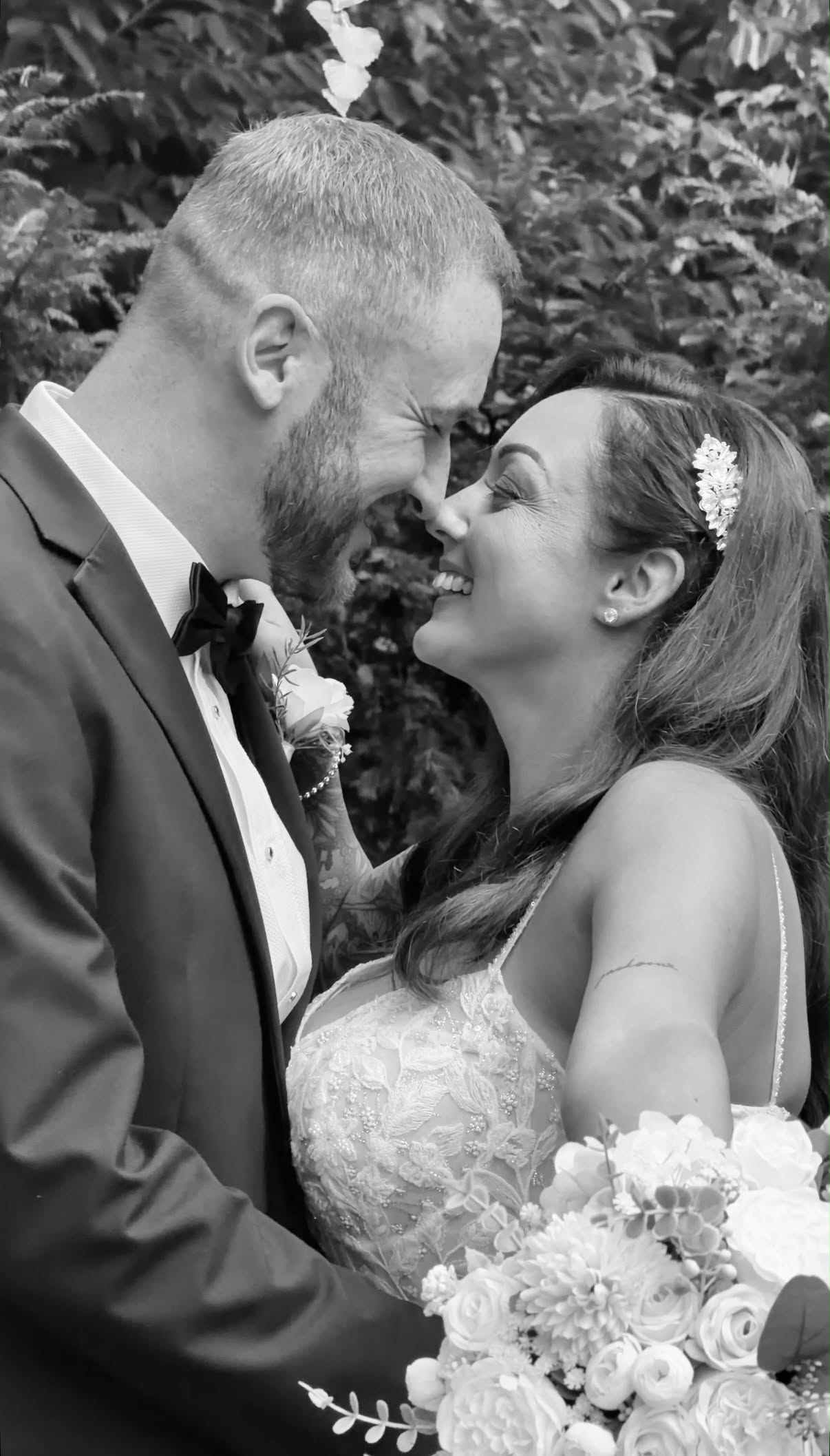 Couple smiling nose to nose with a bouquet