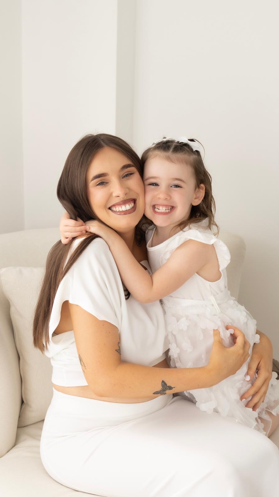 Mother and daughter cheek to cheek, both smiling