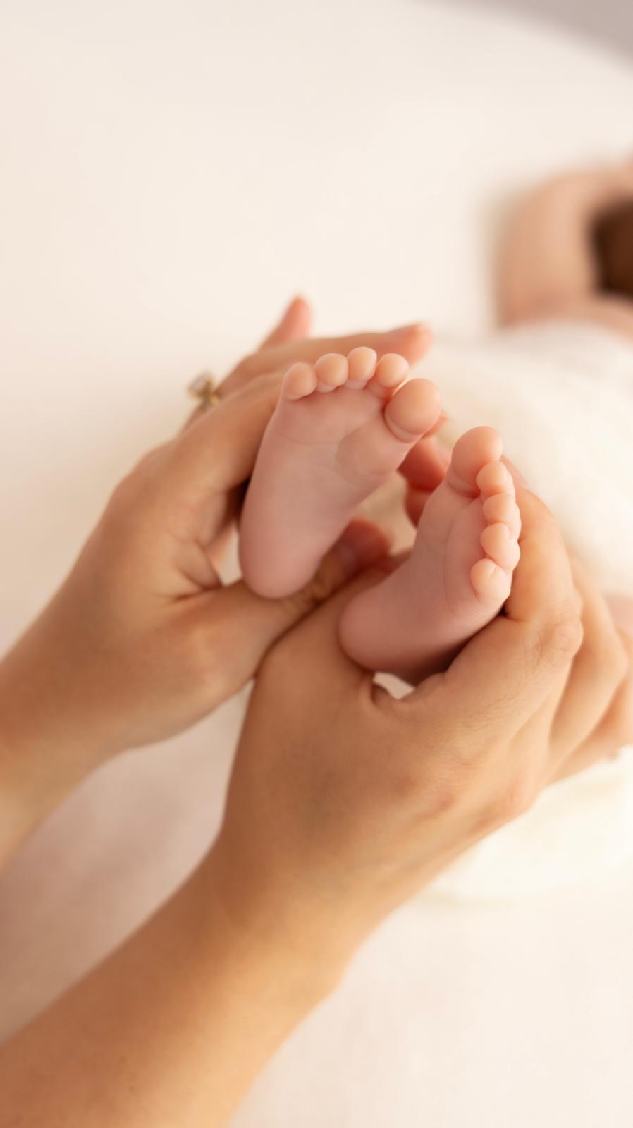 Newborn's tiny feet cradled in mum's hands