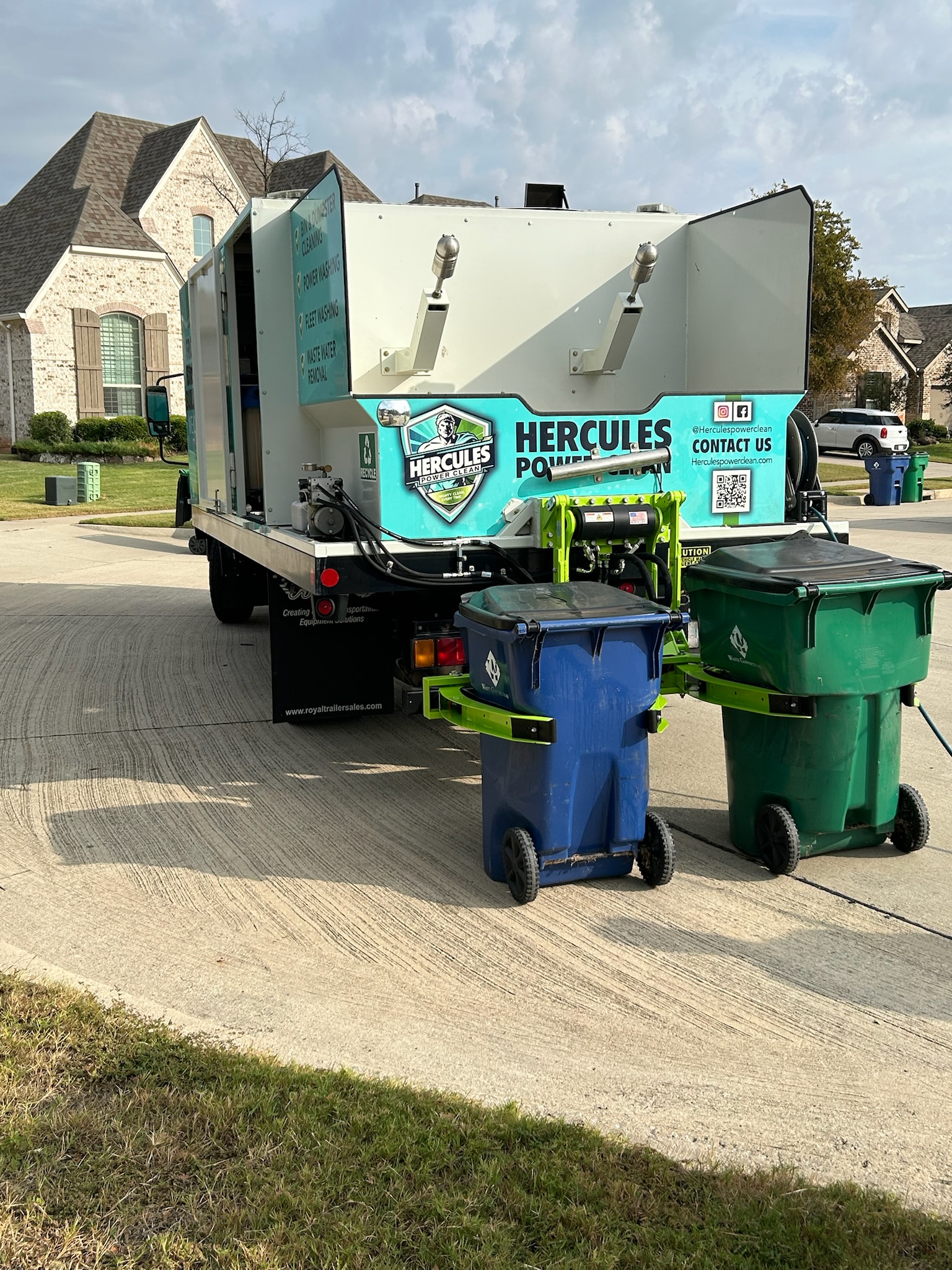 Trash can cleaning service truck washing blue and green trash bins in Texas Professional trash can cleaning truck sanitizing bins in a Texas neighborhood Curbside trash can cleaning service with truck and bins in McKinney Texas