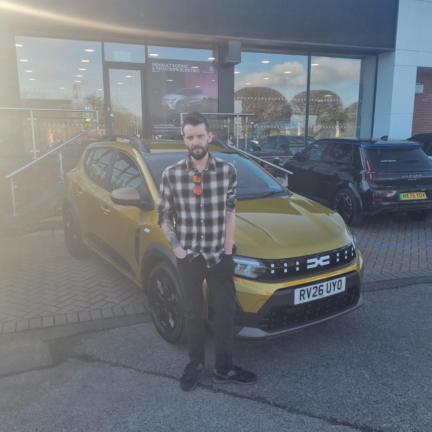 Andy - ACB Driving instructor standing with his gold Dacia Sandero in Woking