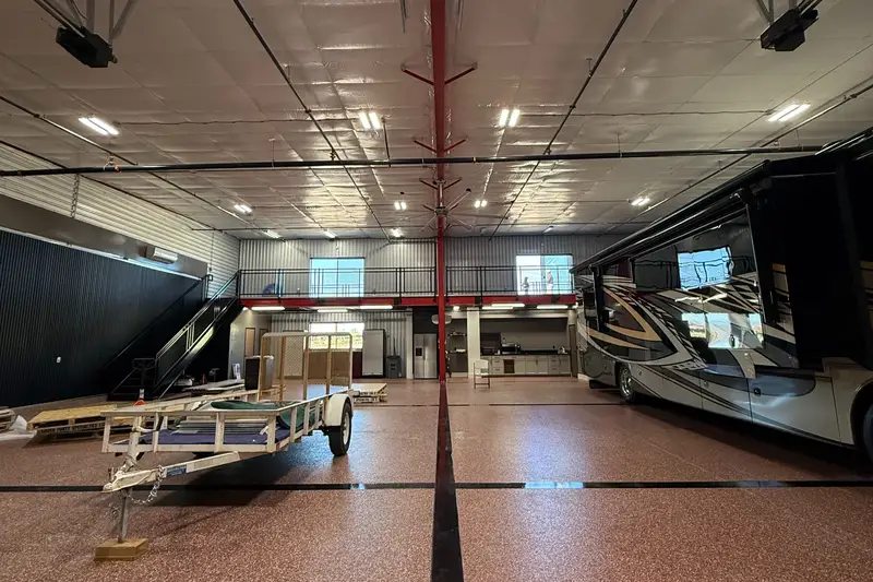Garage interior with a motorcoach and a utility trailer