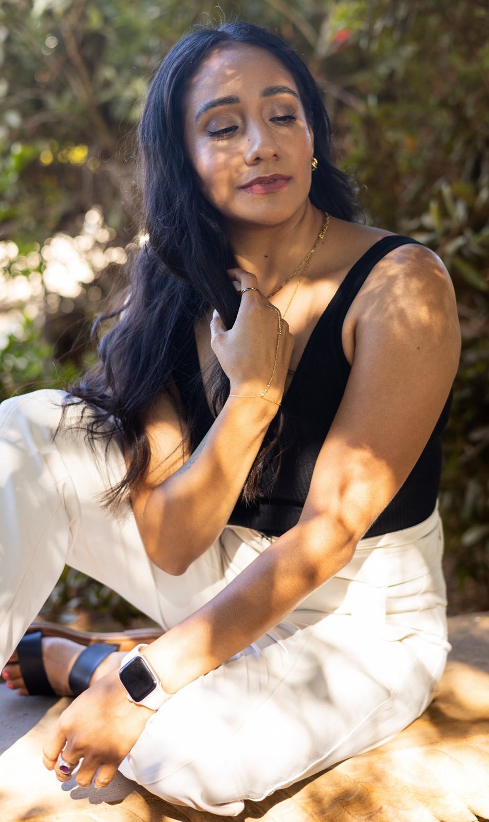 Andrea seated in dappled light with her eyes closed, hand resting at her heart