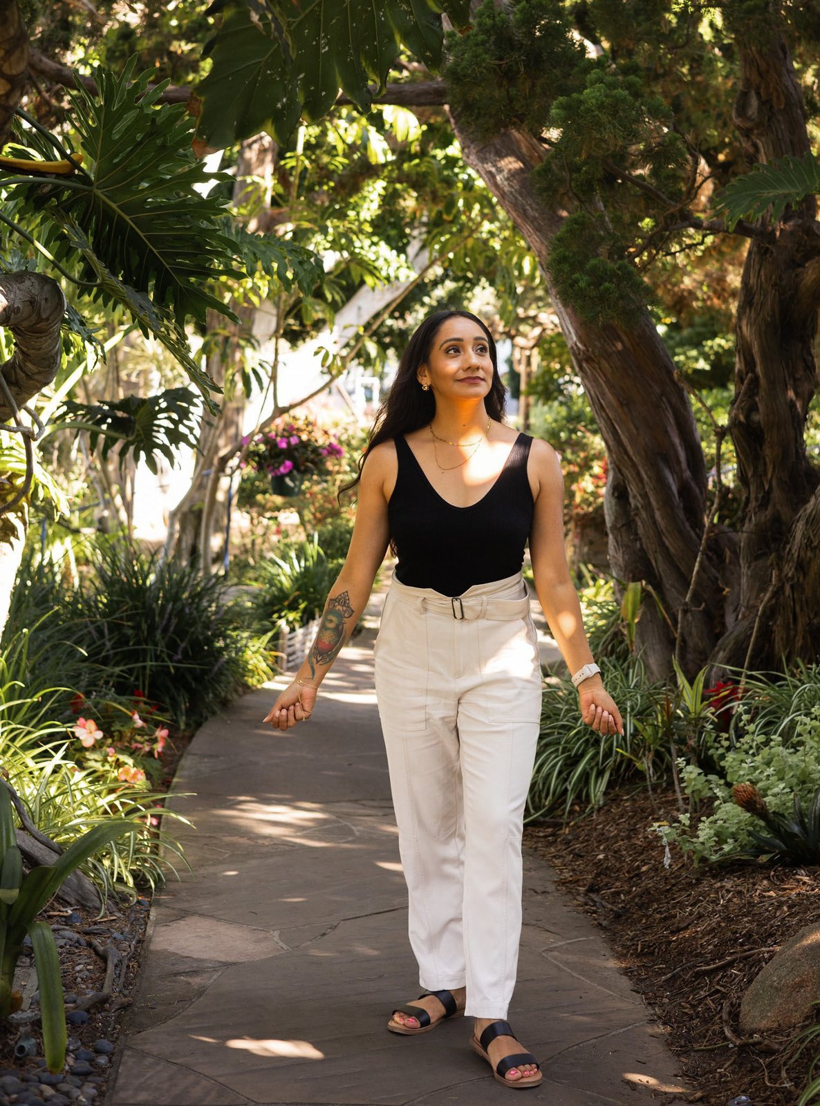 Andrea walking down a garden path, looking up into the trees
