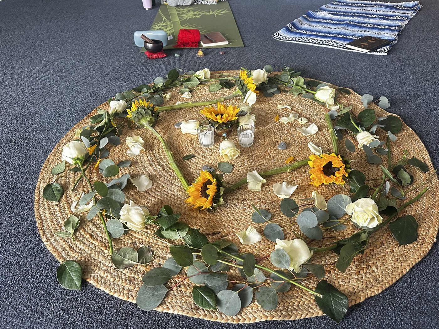 Circle altar of sunflowers, white roses, eucalyptus and candles on a woven mat