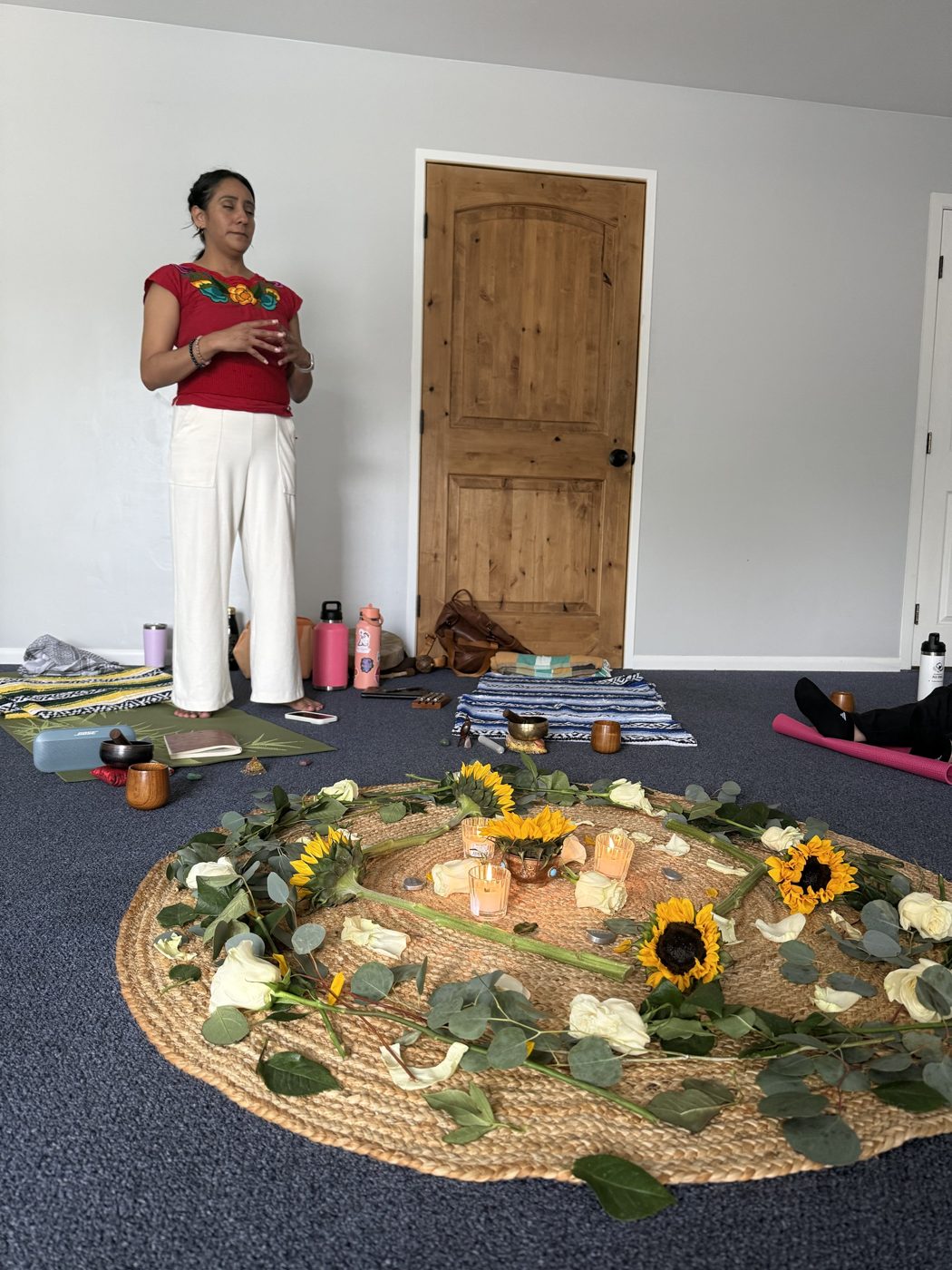 Andrea standing in meditation beside a flower altar during a circle
