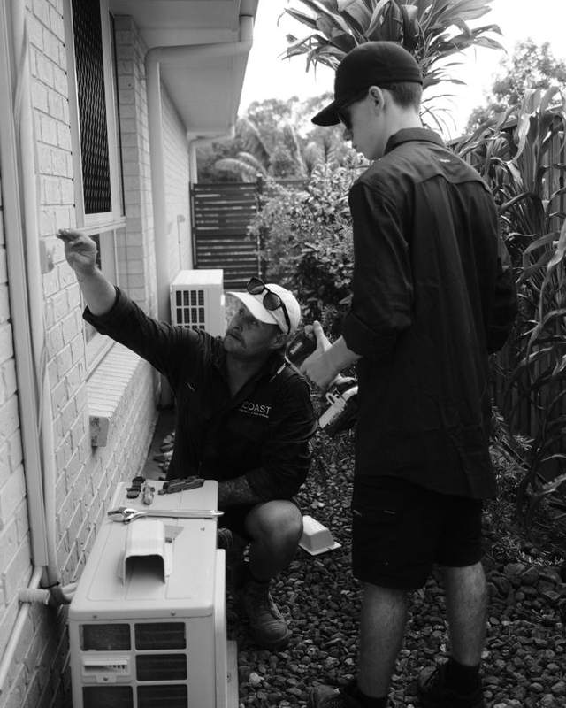Two Coast electricians fitting a split system outdoor unit