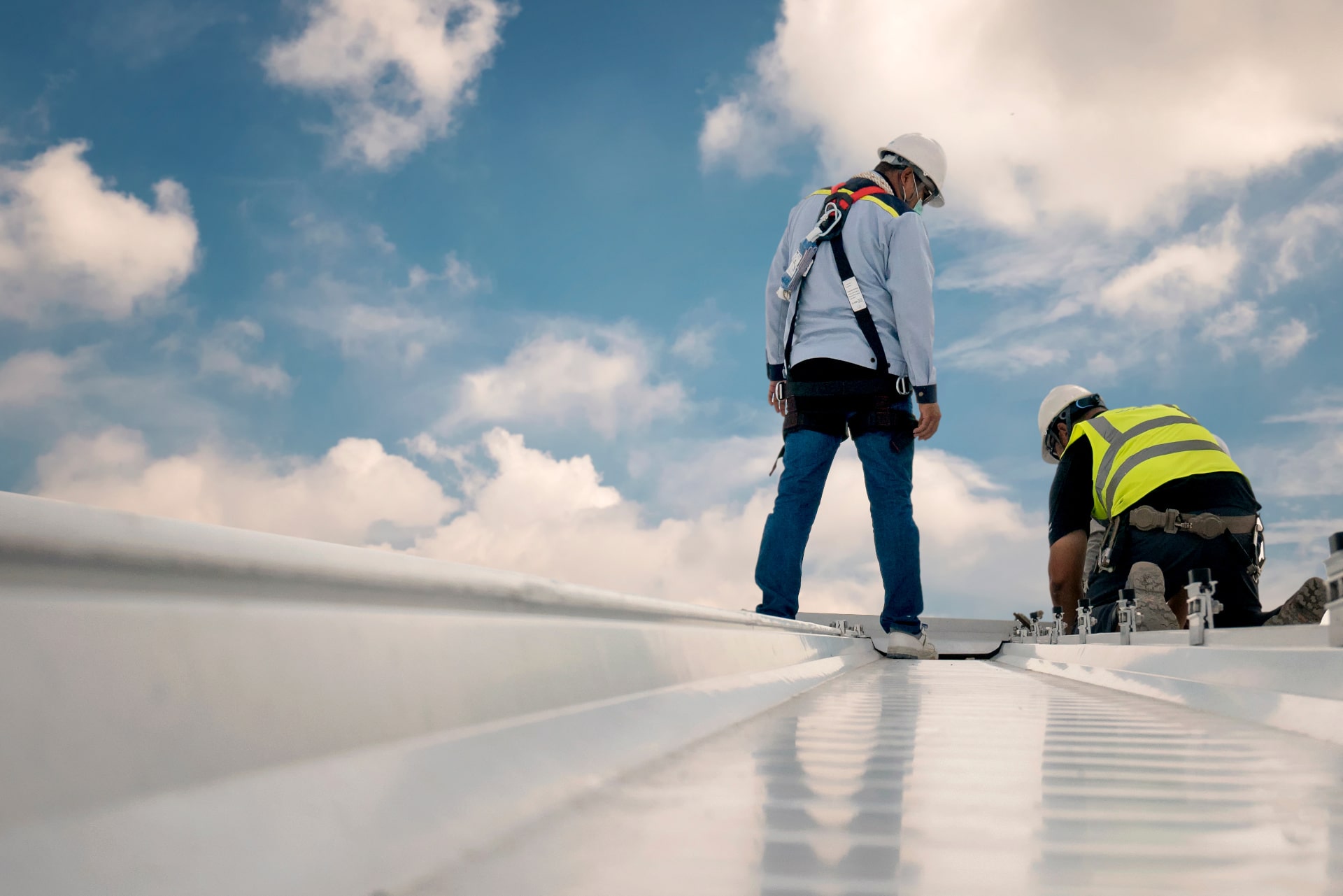 a group of men wearing safety gear on a comercial roof