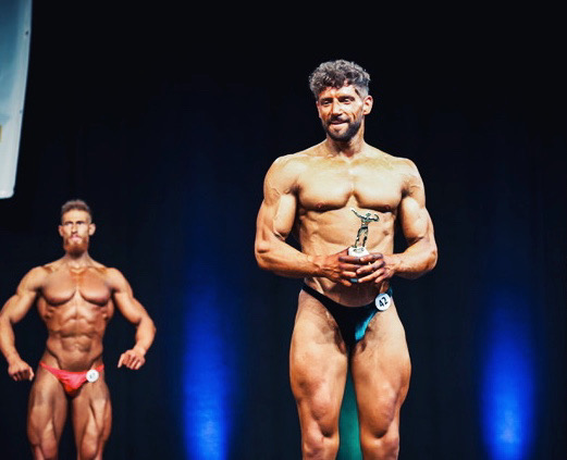 Vincent auf der Bodybuilding-Bühne mit Pokal