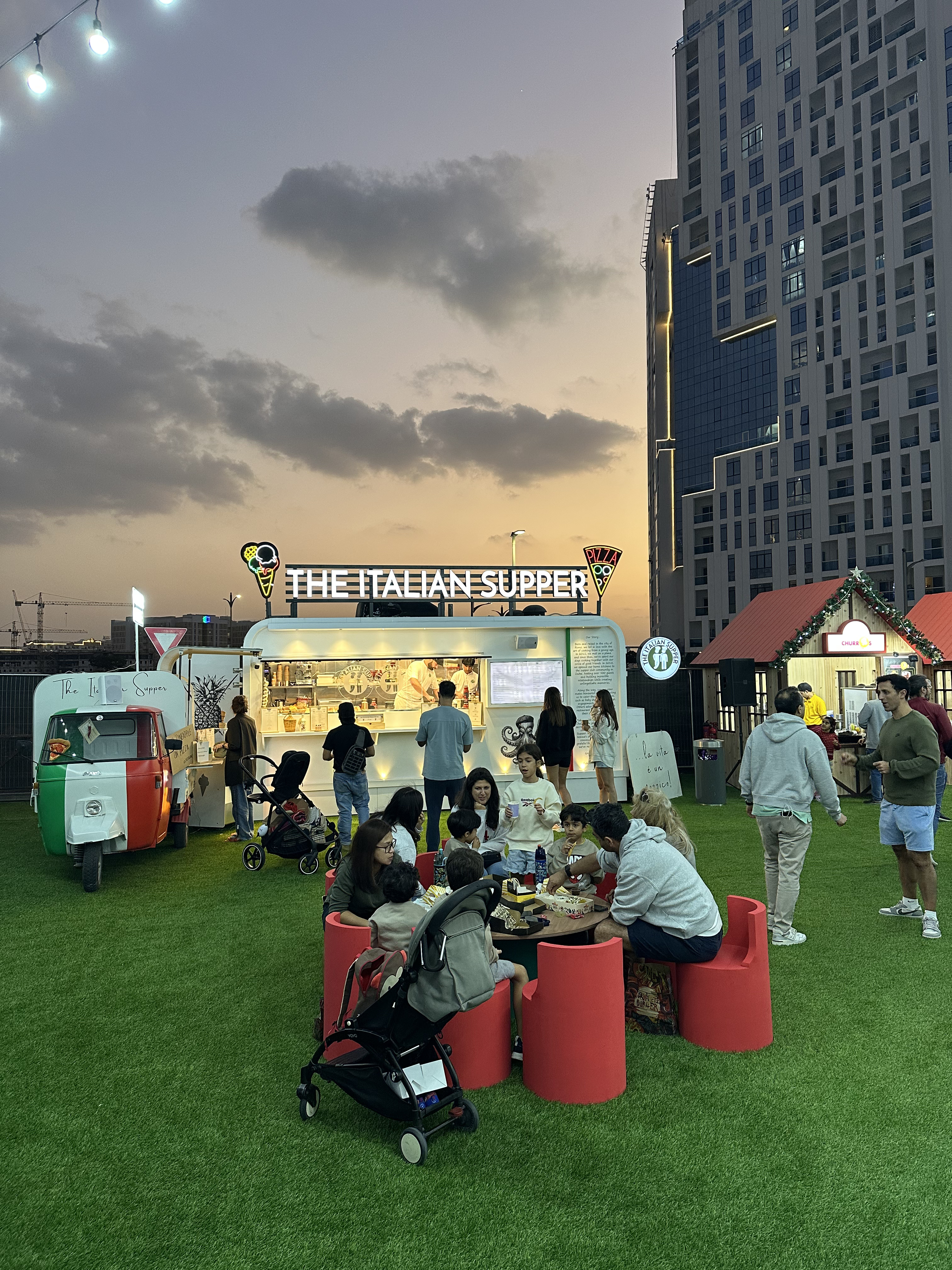 Evening atmosphere at The Italian Supper food truck in Jumeirah Village Circle, Dubai, where families enjoy authentic Italian pizza and desserts under the city lights.