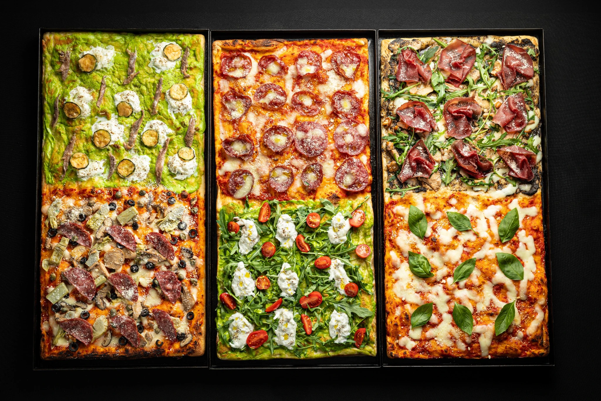 Happy Italian chefs holding a freshly baked pizza inside The Italian Supper kitchen in Dubai