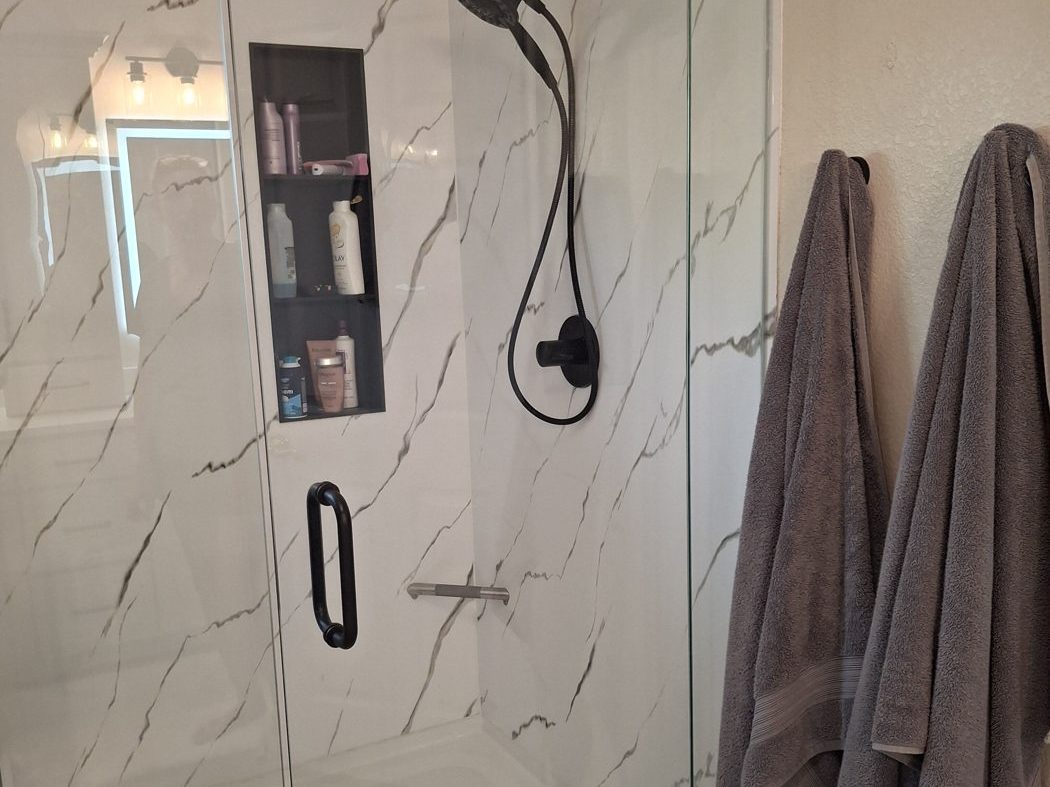 Custom tile shower with marble-look walls and black fixtures in Denver, CO